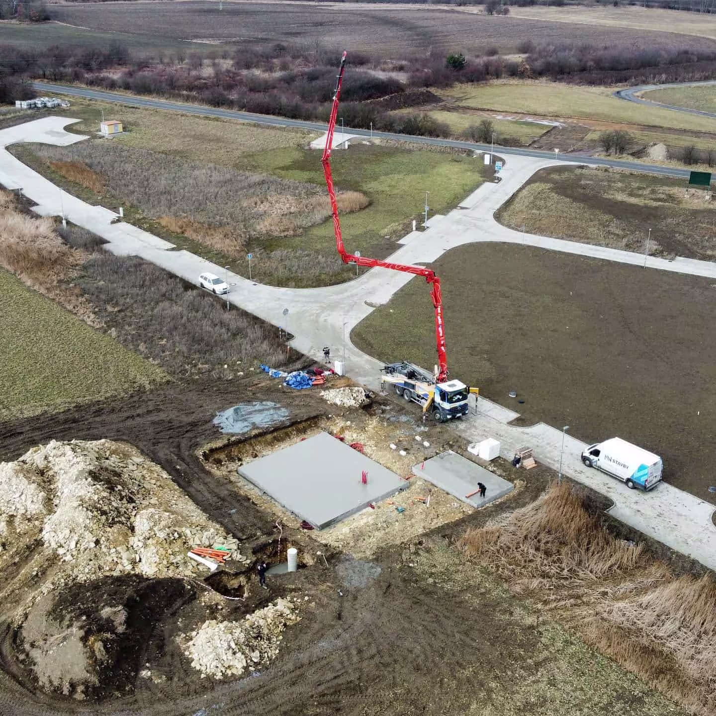 Letecký pohled na proces betonáže základové desky v Dolanech. NNstavby využívá moderní techniku pro rychlou a kvalitní realizaci základů.