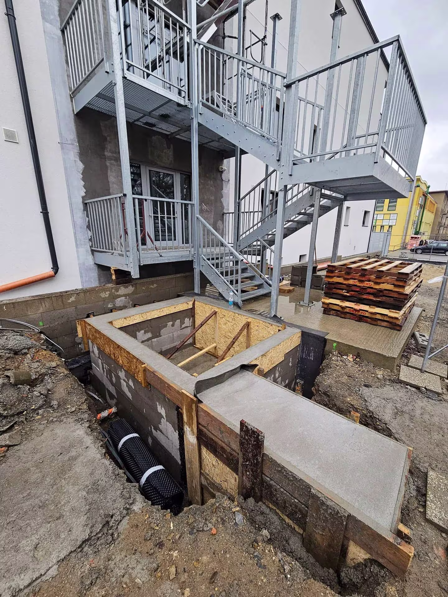 Stavební práce na dřevěném bednění pro betonové základy budoucí výtahové šachty.