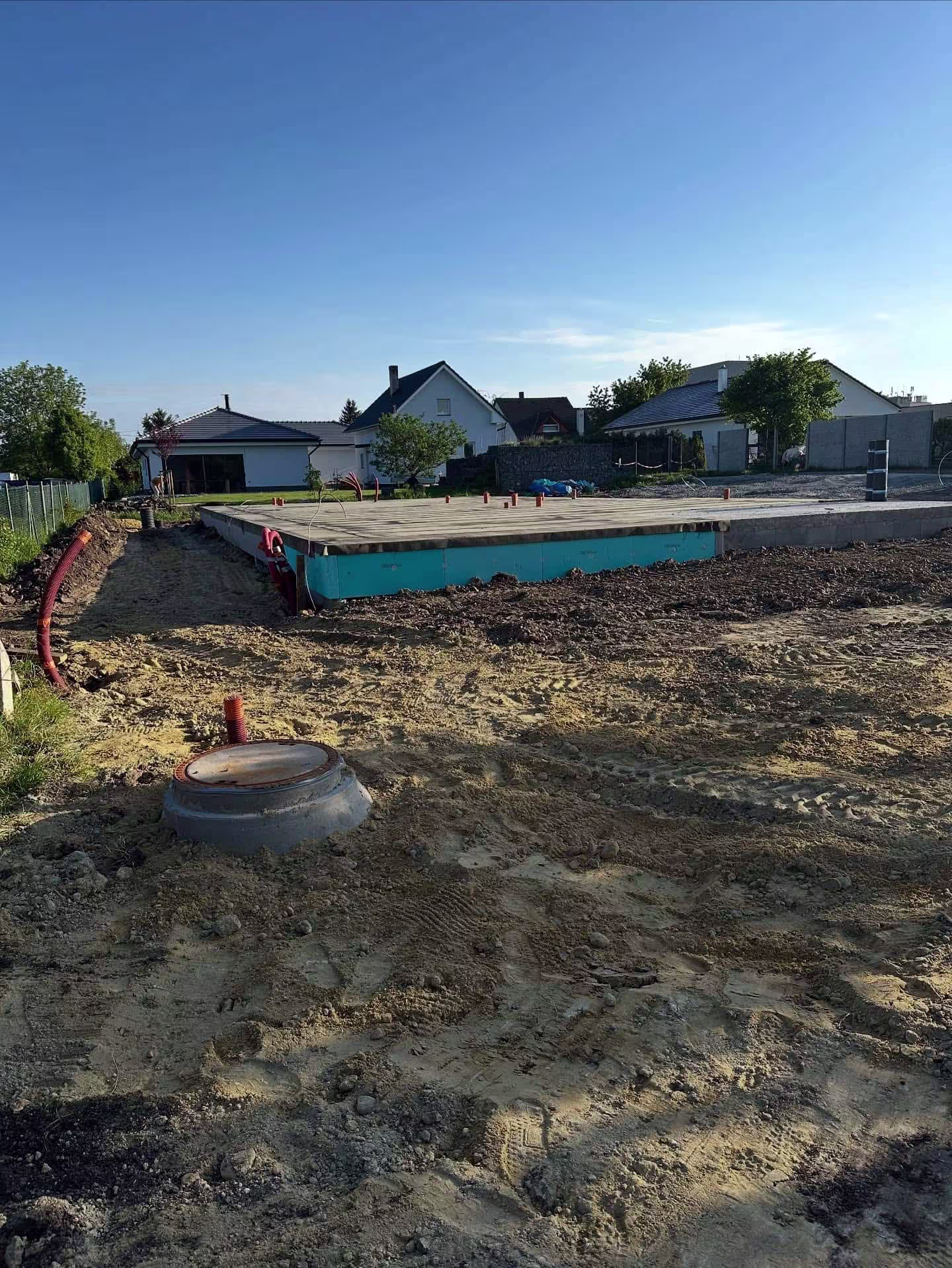 Dokončená realizace jímky v Čakovicích, kde je vidět pouze poklop a kompletně srovnaný terén.