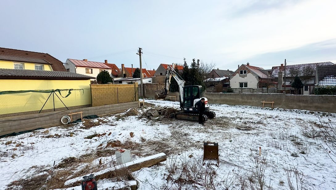 Příprava terénu a odklízení zbytků po demolici pro novou základovou desku v Brodcích v zimních podmínkách od nnstavby.